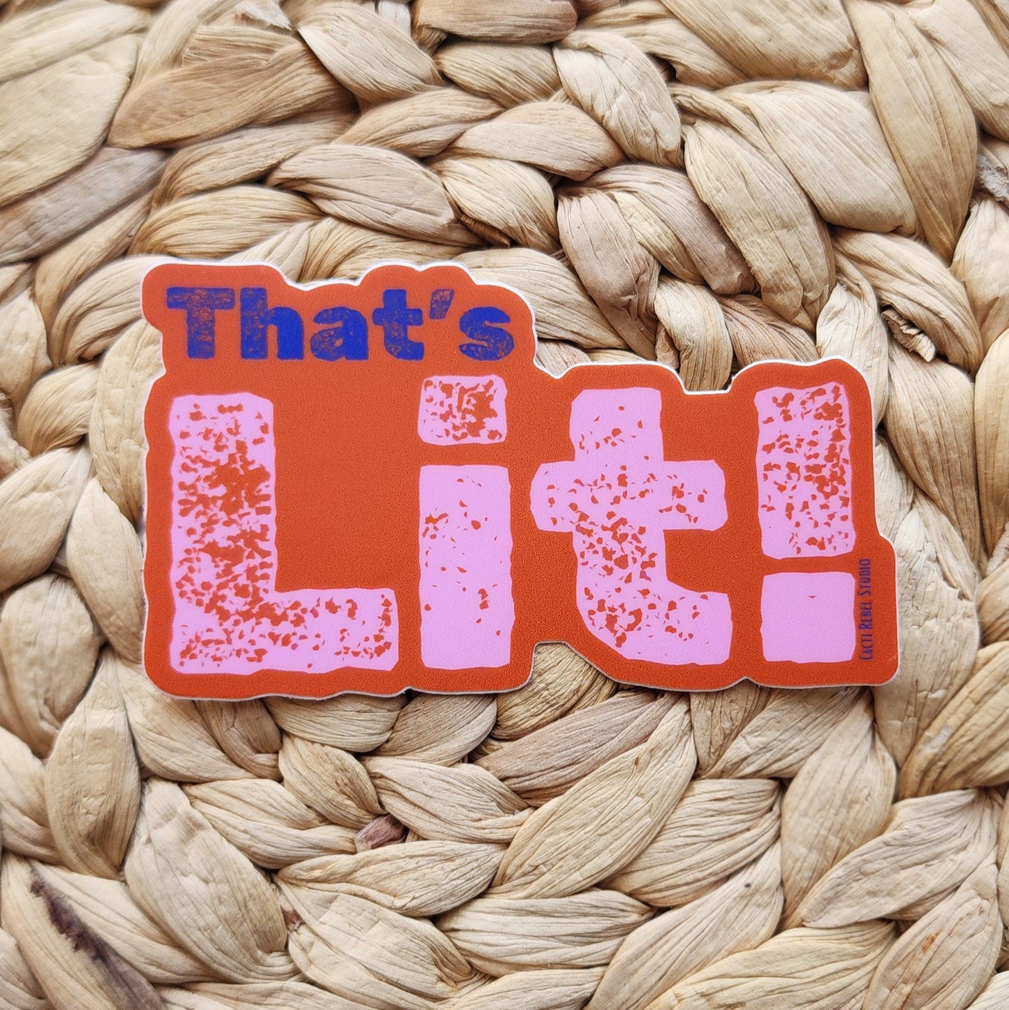 Sticker with 'That's Lit!' text on a woven mat background