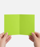 Green card held between two hands on a white background