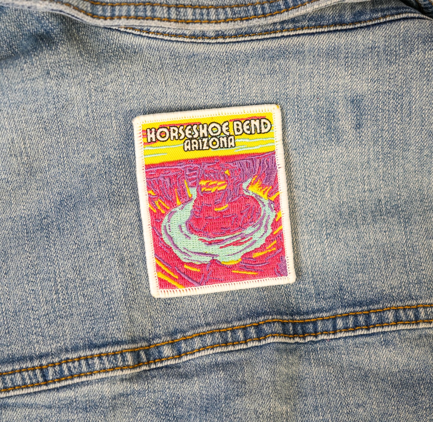 A colorful patch with the text 'Horseshoe Bend Arizona' displayed on the back of a denim jacket.